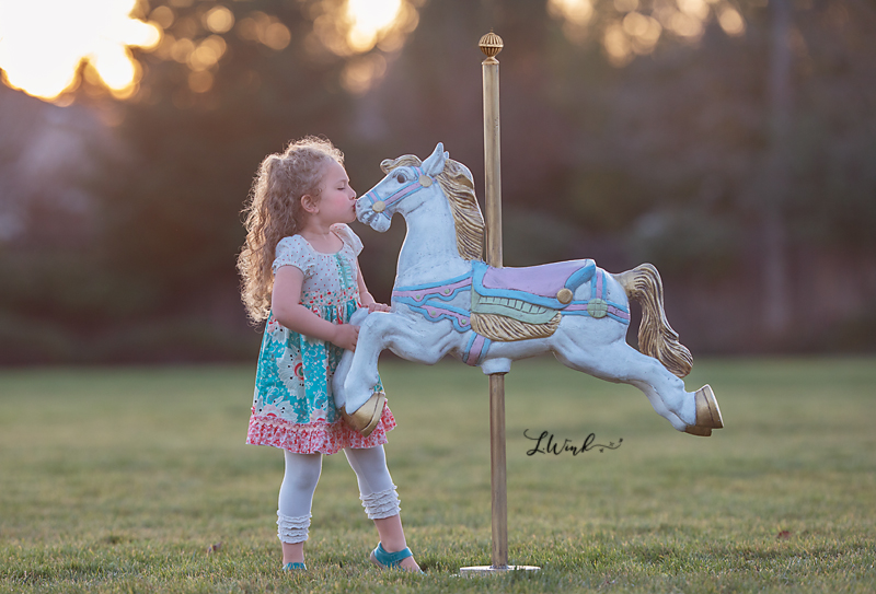 curly haired girl gives carousel horse kisses