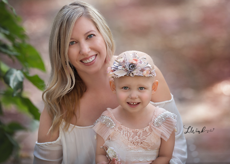 Mom and daughter in lap up close wearing pink princess dress and floral crown