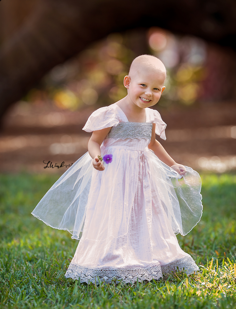  little bald girl in pink and silver princess dress smiling