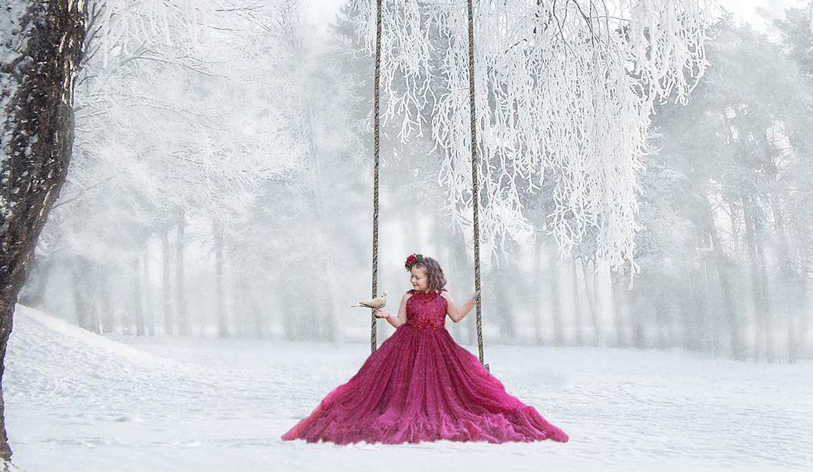 Girl in dress sitting in snow swing