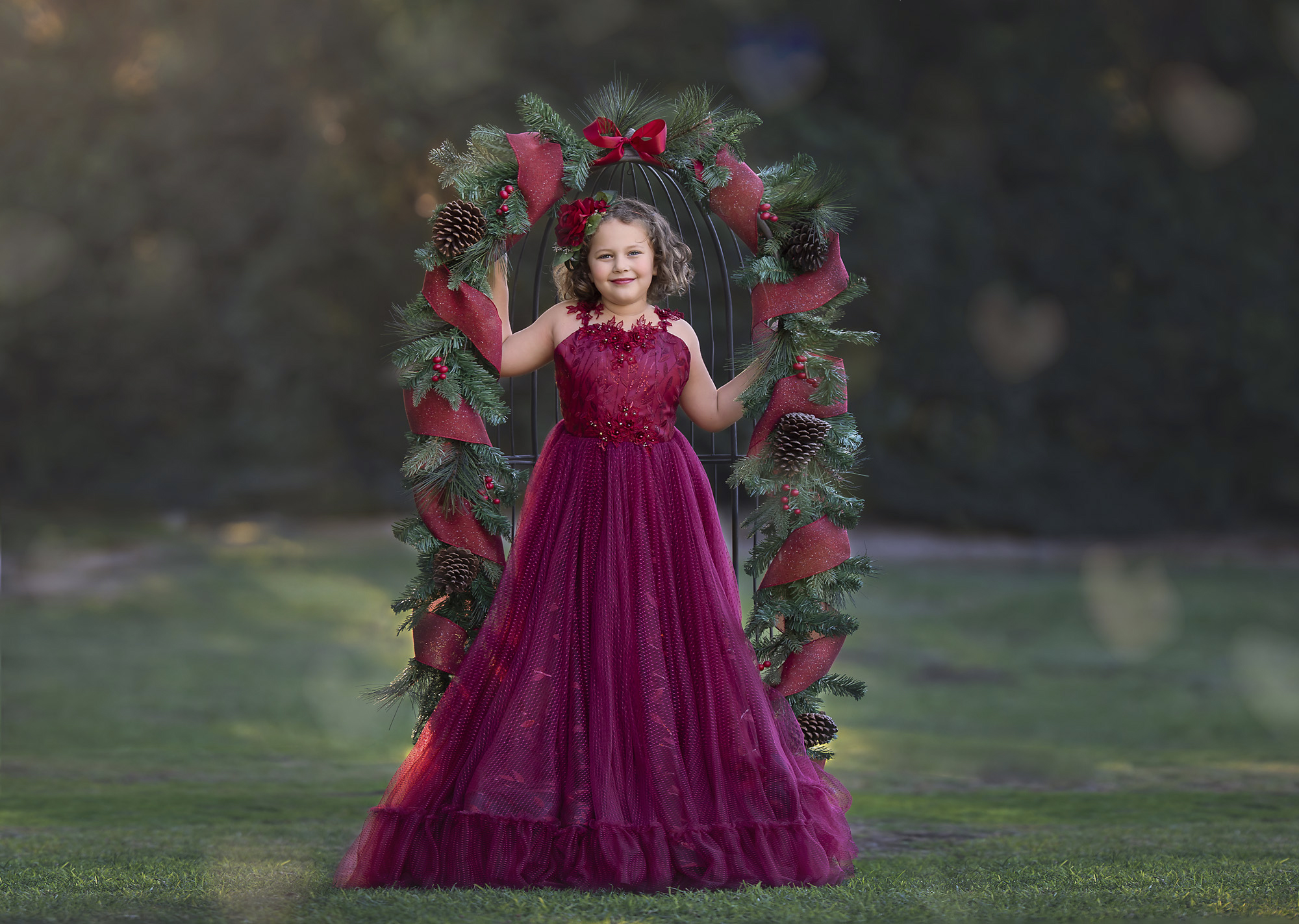 Girl standing in holiday garland chair on grass