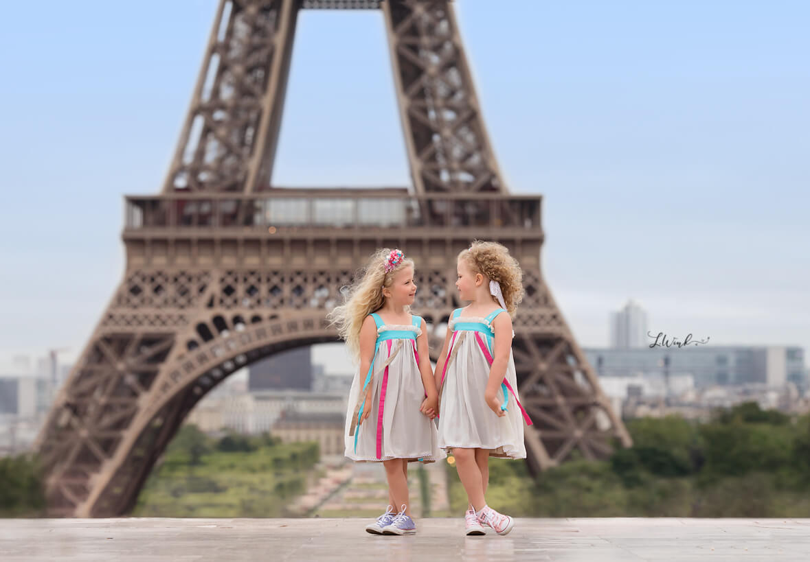 Twin sisters look at each other in front of Eiffel Tower