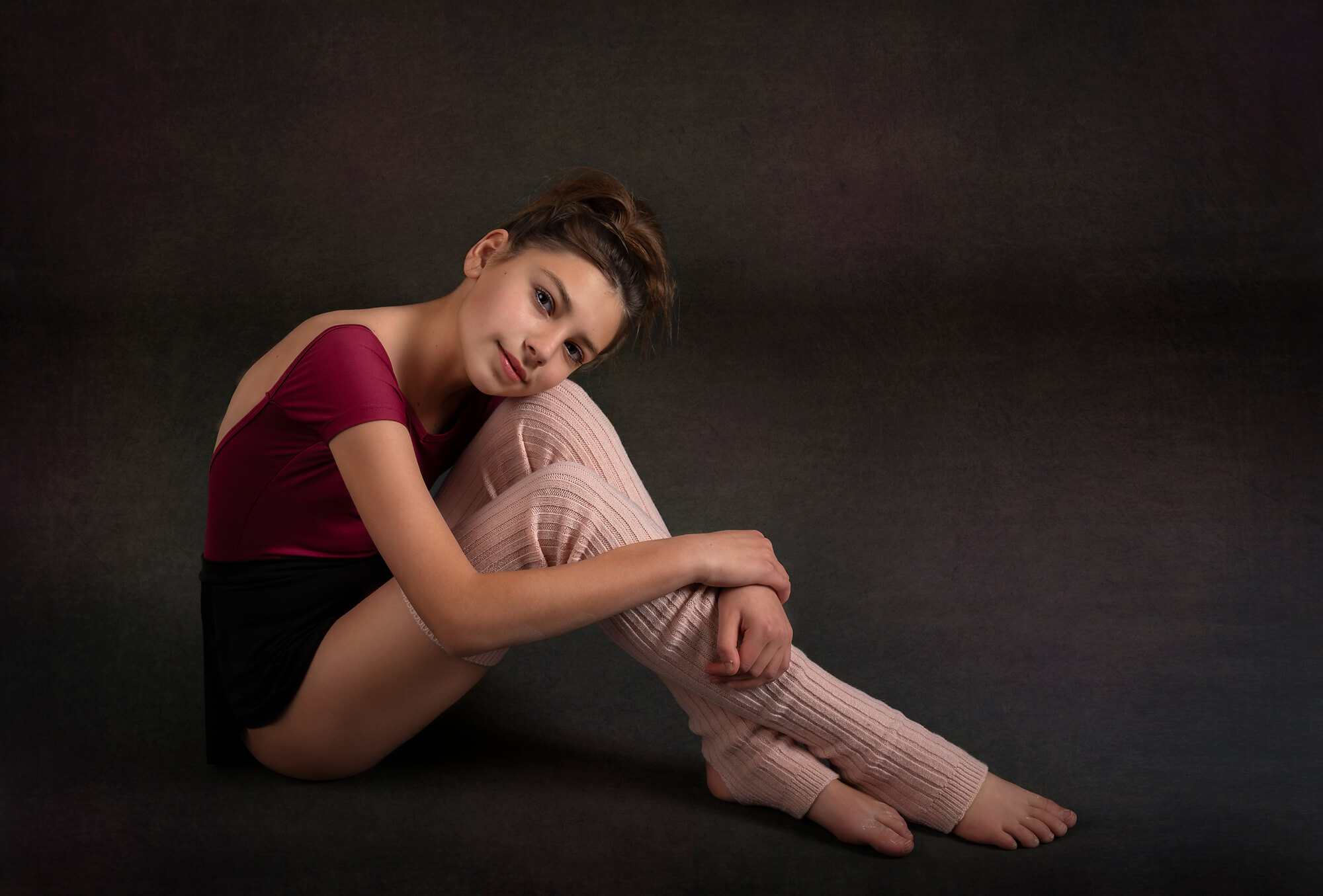 dancer girl resting head on knees in leg warmers and leotard