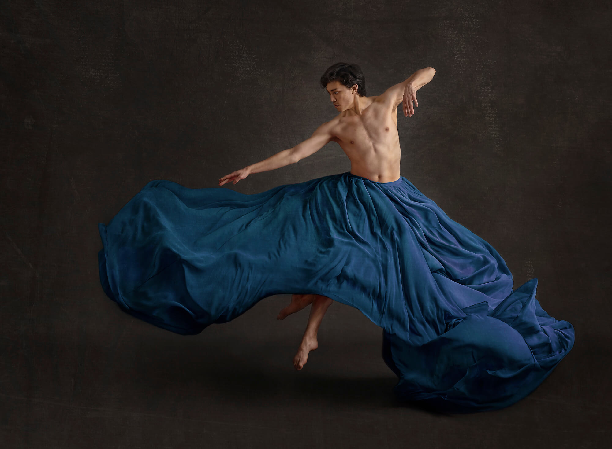 Male dancer jumping in a blue skirt in L.A. photography studio