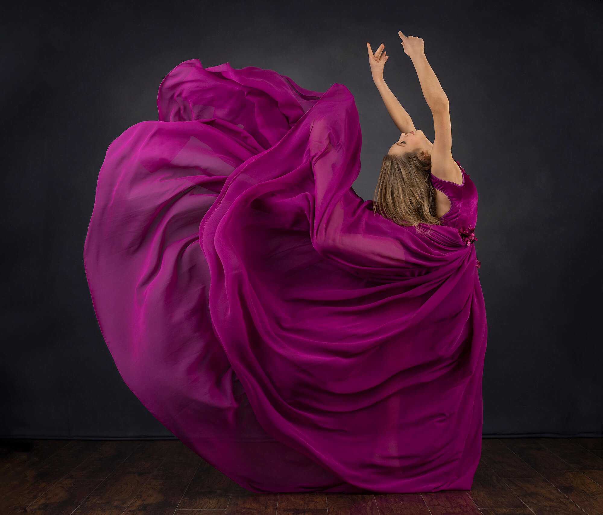 Ballerina kicking up in magenta dress in Los Angeles photography studio