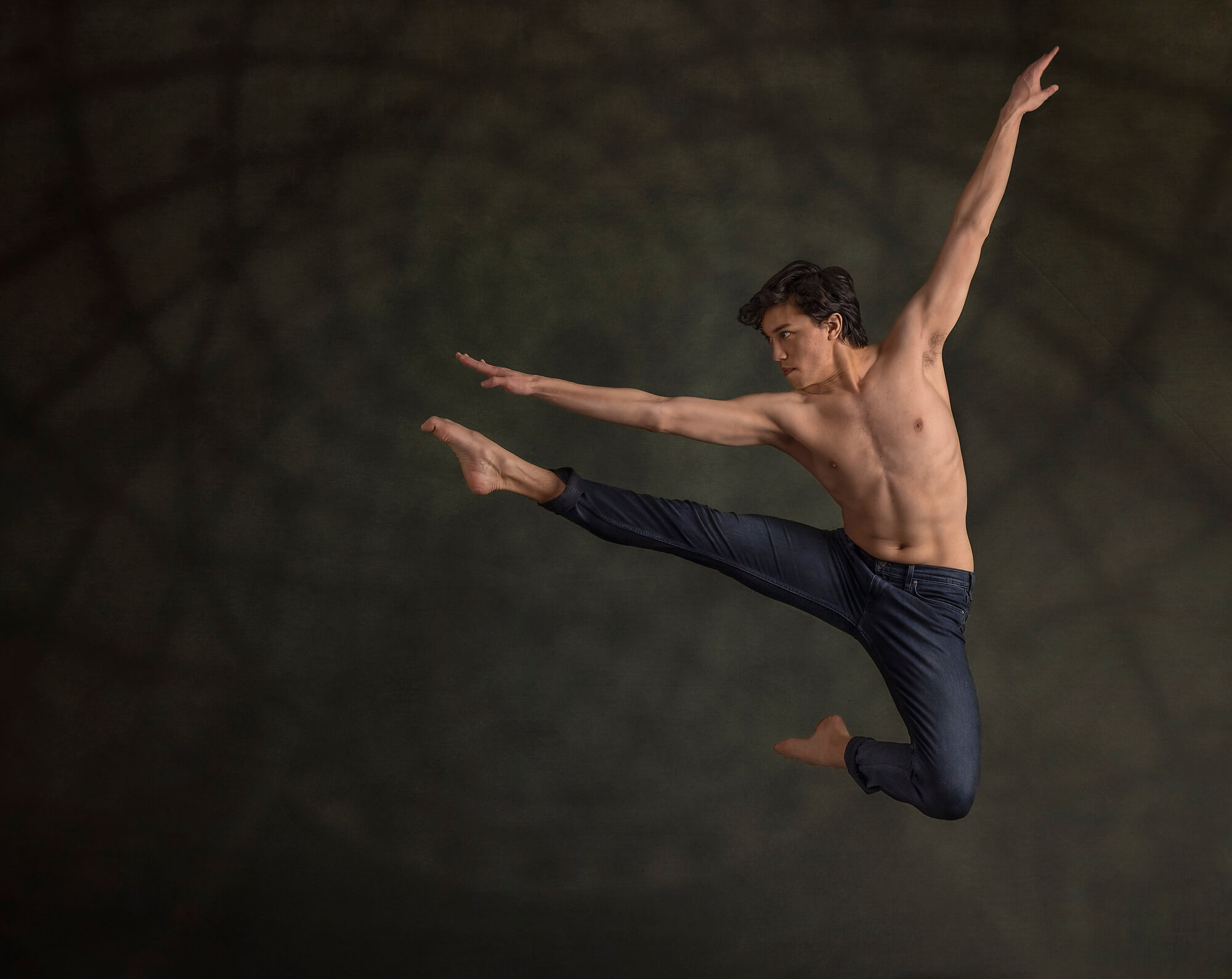 CA male dancer jumping in portrait studio wearing jeans and no shirt