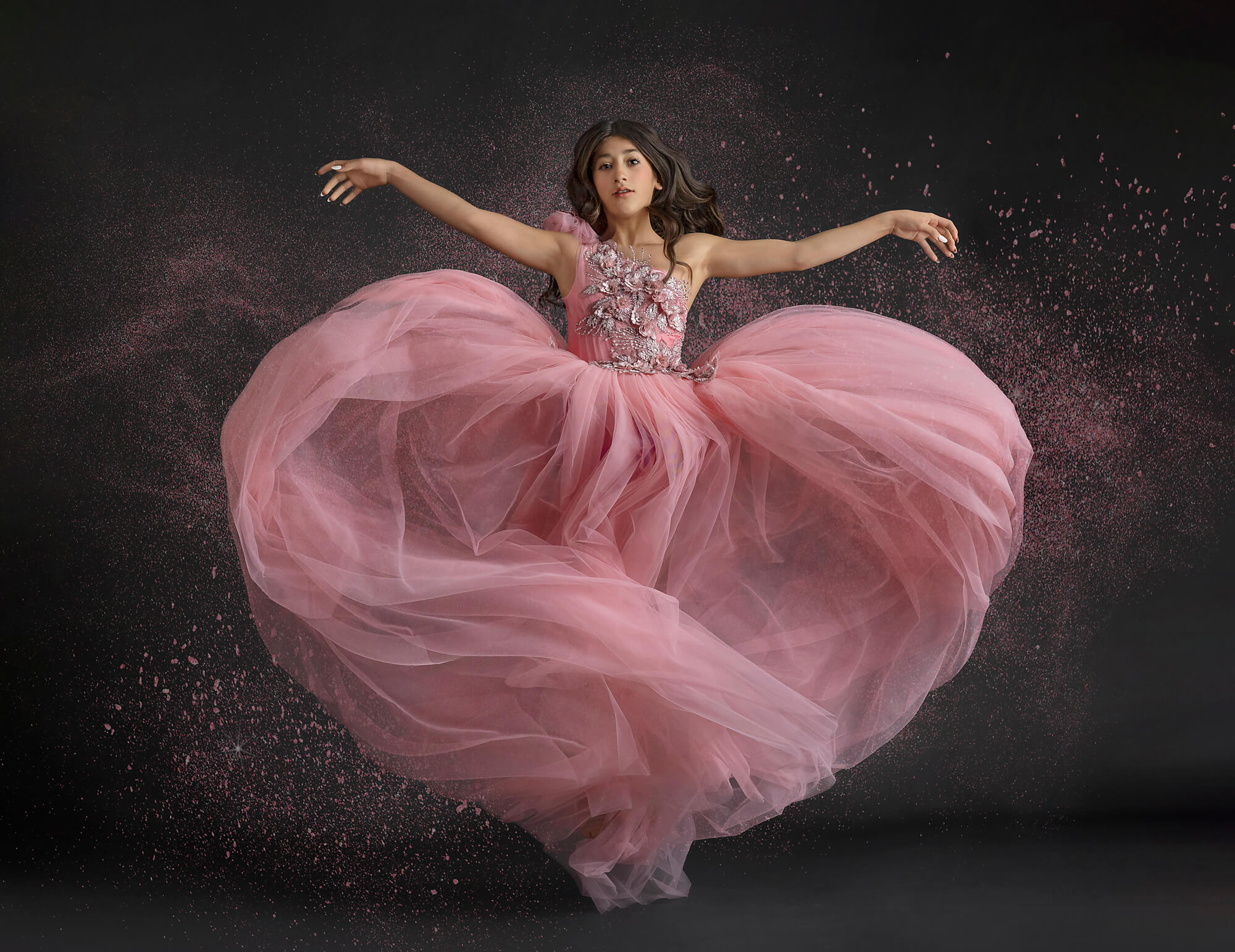 Tween girl jumping in pink dress in photo studio