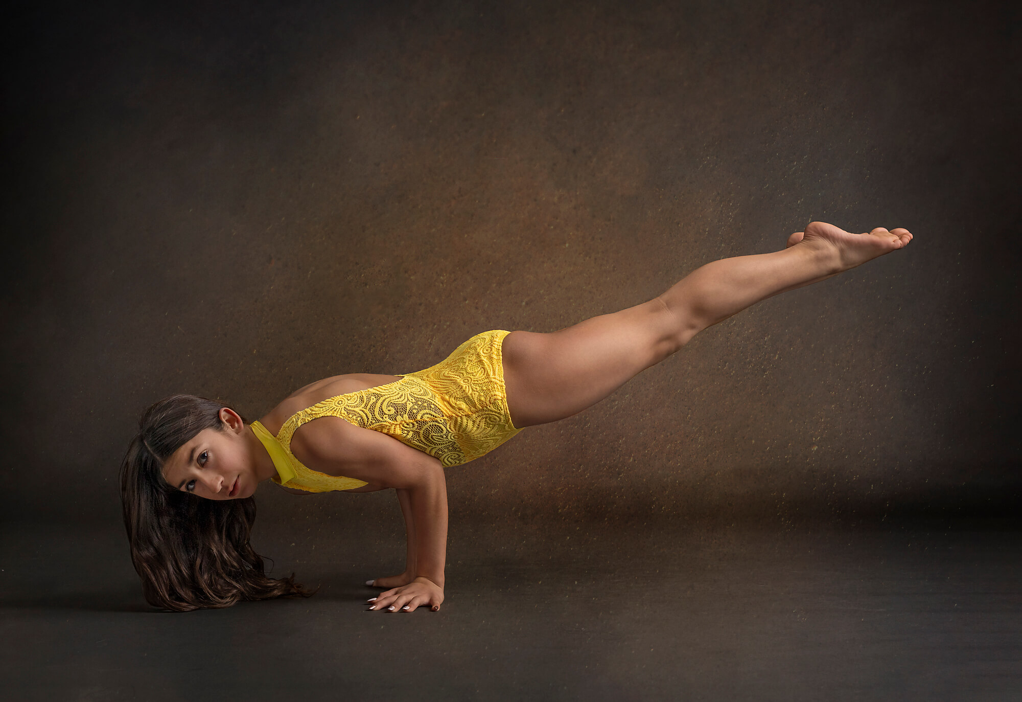 Teen dancer wearing yellow balancing in a plank pose